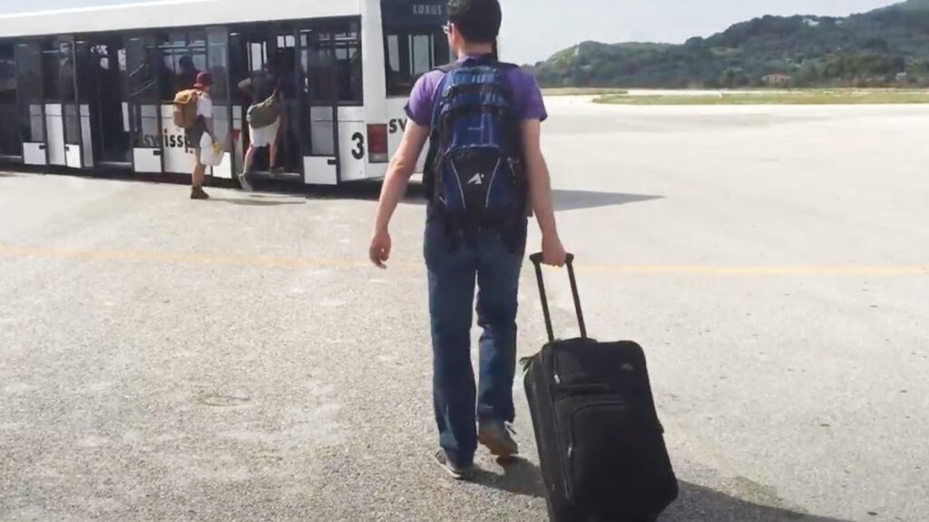 Man with suitcase getting on bus.